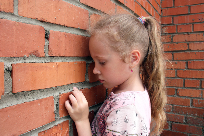 An anxious girl standing in front of a brick wall